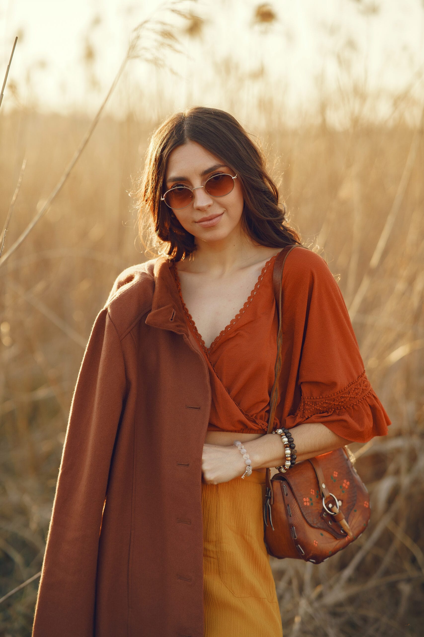 Ragazza con camicia arancione, gonna giallo ocra e cappotto marrone