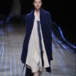 Modella con cardigan lungo blu sopra un vestito bianco