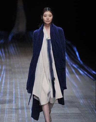 Modella con cardigan lungo blu sopra un vestito bianco