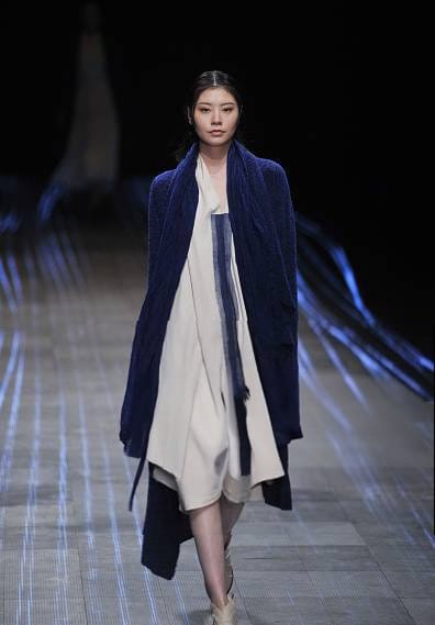 Modella con cardigan lungo blu sopra un vestito bianco