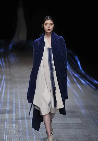 Modella con cardigan lungo blu sopra un vestito bianco