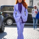 Una ragazza con i capelli rossi indossa camicia viola intenso e un completo viola più chiaro