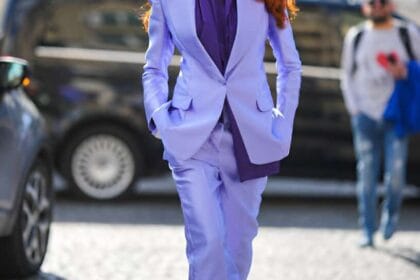 Una ragazza con i capelli rossi indossa camicia viola intenso e un completo viola più chiaro