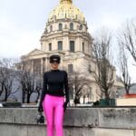 Donna con maglia nera, guanti e legging-boots fucsia, in piedi di fronte al Dome des Invalides, Parigi.