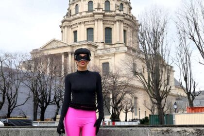 Donna con maglia nera, guanti e legging-boots fucsia, in piedi di fronte al Dome des Invalides, Parigi.