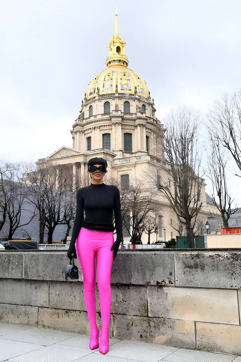 Donna con maglia nera, guanti e legging-boots fucsia, in piedi di fronte al Dome des Invalides, Parigi.