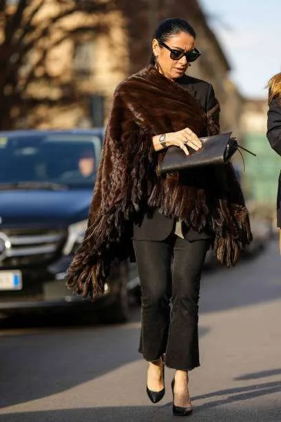 Donna indossa mantella in pelliccia marrone e pantaloni neri