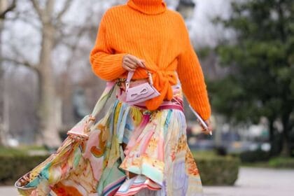 Donna indossa gonna lunga di tendenza a balze colorata, maglia arancione e occhiali da sole