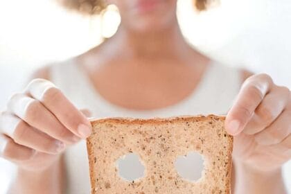 Simbolo dell'intolleranza al glutine: Una donna mostra una fetta di pane con intagliati occhi e bocca triste