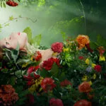 Donna rilassata ricoperta di fiori ed erbe, simbolo del benessere