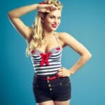 Ragazza bionda vestita stile marinara, con top a righe blu e shorts blu