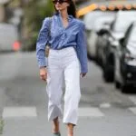 Donna indossa outfit primaverile con camicia a righe blu e pantaloni crop bianchi