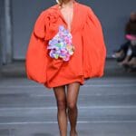 Modella sfila in abito arancione. L'arancione e il giallo citron sono colori vitaminici di tendenza.