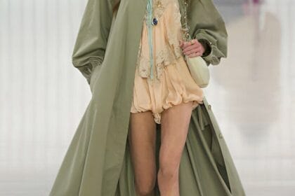 Modella indossa trench lungo verde salvia e minidress rosa cipria, outfit classico moda primaverile