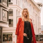 Ragazza con vestito nero e trench corallo. Un outfit chic che può essere creato senza spendere soldi