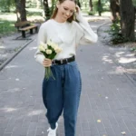 Ragazza in un parco indossa jeans balloon e maglietta bianca