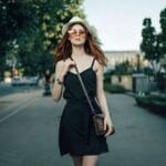 Ragazza indossa un vestitino nero e borsa a tracolla. Vestirsi bene è una forma di self-care.