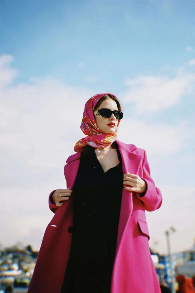 Donna indossa foulard e cappotto fucsia