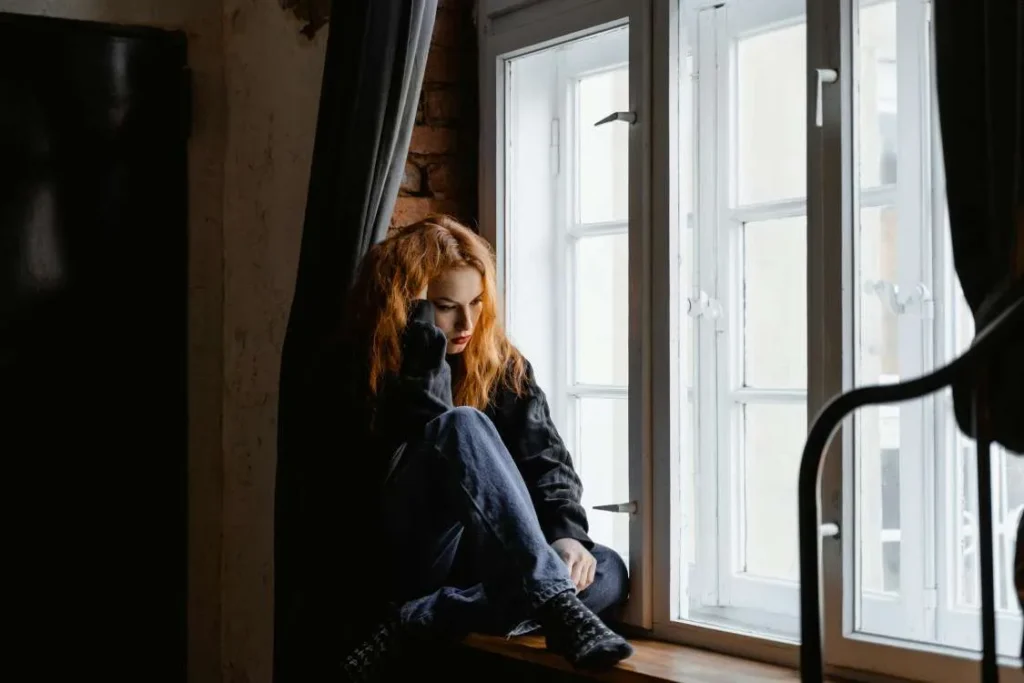 Donna vittima di gaslighting seduta davanti a una finestra