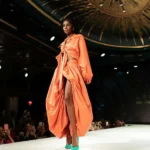 Modella sfila con un outfit arancione e scarpe décolleté verde smeraldo