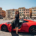 Donna con tubino nero scende da una macchina rossa sportiva