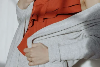 Donna con blusa arancione e cardigan lungo grigio chiaro