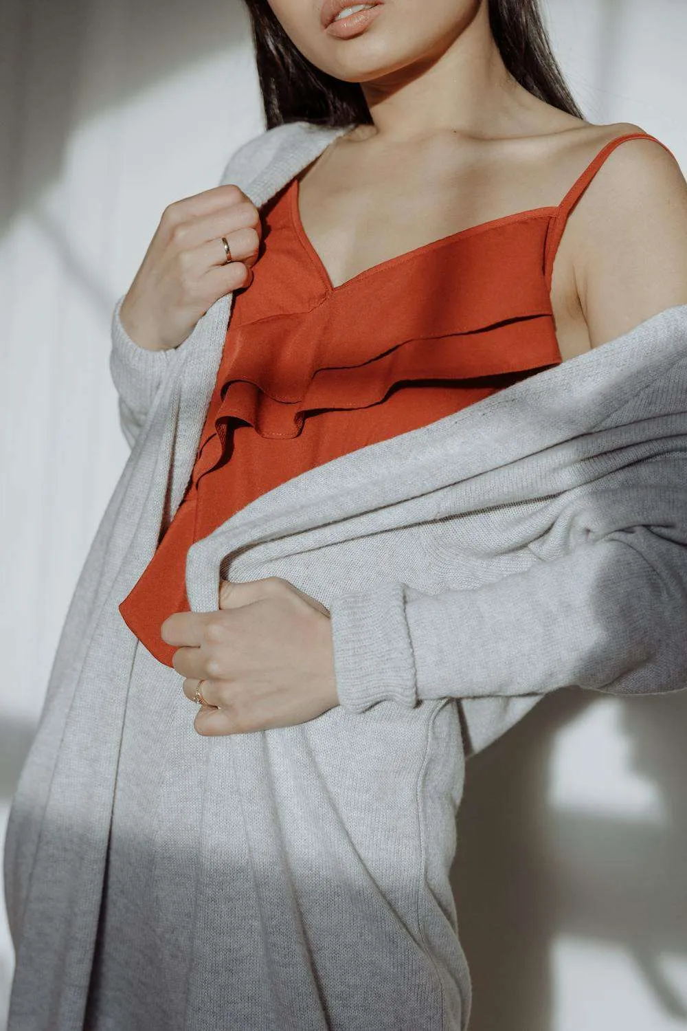 Donna con blusa arancione e cardigan lungo grigio chiaro