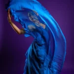 Donna balla alzando un lembo del suo abito blu in chiffon. Vestirsi di blu può influenzare l'umore.