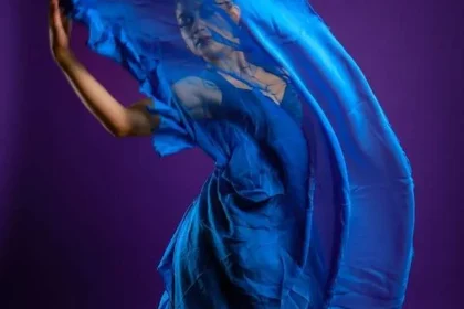 Donna balla alzando un lembo del suo abito blu in chiffon. Vestirsi di blu può influenzare l'umore.