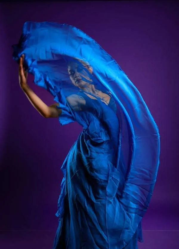 Donna balla alzando un lembo del suo abito blu in chiffon. Vestirsi di blu può influenzare l'umore.