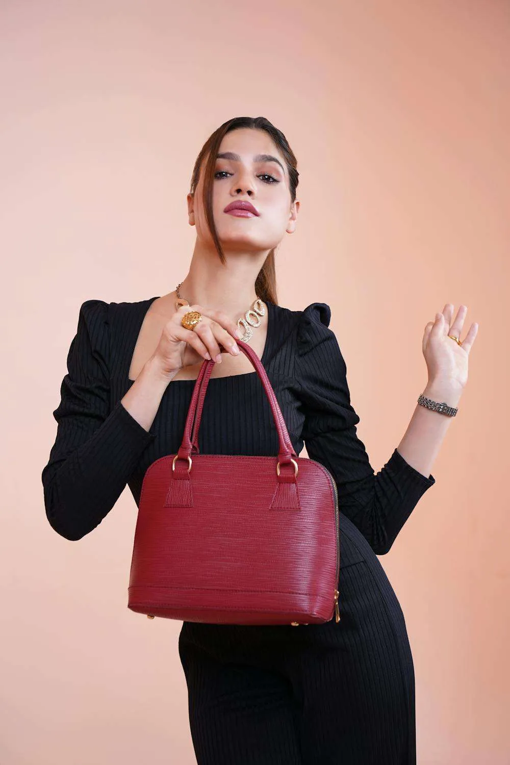 Donna con tubino nero e borsa strutturata rossa per un look minimal chic