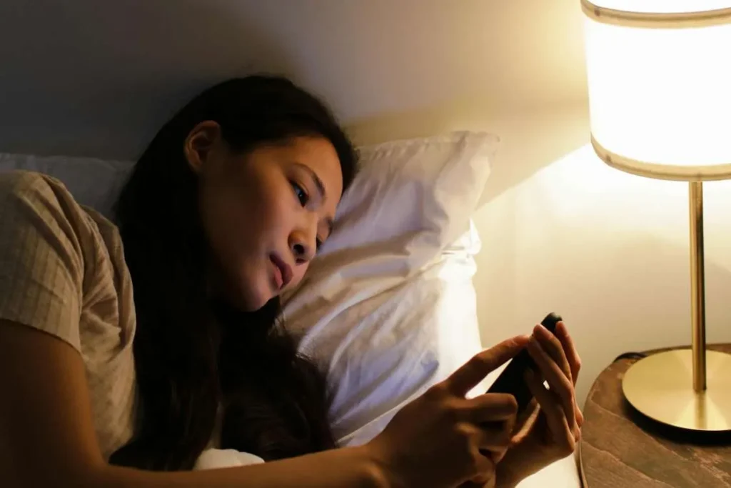 Donna a letto controlla il suo smartphone