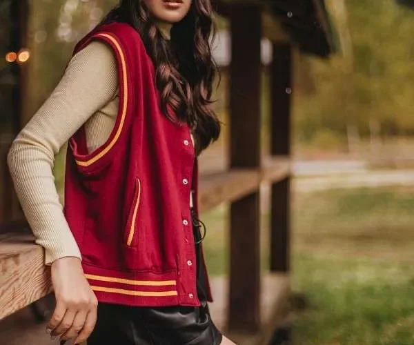 Ragazza indossa layering autunnale con maglia, gilet sportivo e minigonna nera