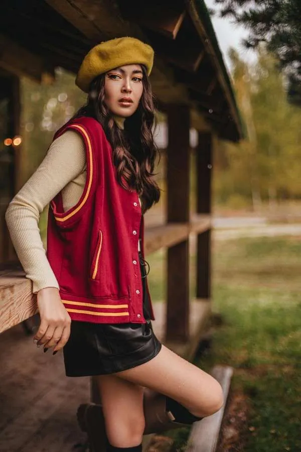 Ragazza indossa layering autunnale con maglia, gilet sportivo e minigonna nera