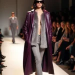 Modella sfila con lungo cappotto rosso borgogna in pelle e pantaloni grigi, colori di tendenza moda autunno inverno 2025, 2026