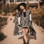 Donna con poncho bianco e nero a motivi geometrici e bordo a frange