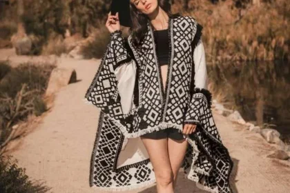 Donna con poncho bianco e nero a motivi geometrici e bordo a frange