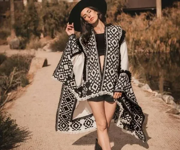 Donna con poncho bianco e nero a motivi geometrici e bordo a frange