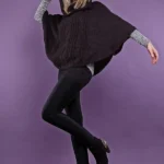 Donna con poncho marrone, leggings e stivaletti neri.
