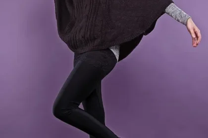 Donna con poncho marrone, leggings e stivaletti neri.