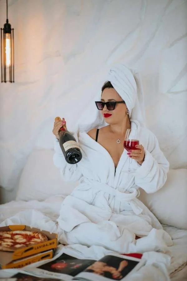 Donna single festeggia felicemente San Valentino con pizza, calice di vino, riviste di moda.