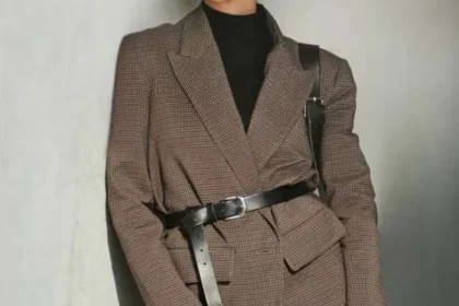 Una donna indossa un blazer oversize marrone stretto in vita da una cintura in pelle nera.