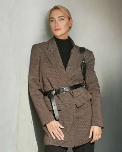 Una donna indossa un blazer oversize marrone stretto in vita da una cintura in pelle nera.