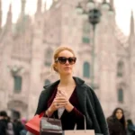 Donna elegante con borse di boutique a Milano: esempio di shopping consapevole e di qualità durante i saldi.