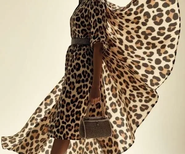 Modella indossa ampio abito con stampa animalier leopardata e scarpe con tacco alto a stiletto
