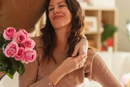 Coppia festeggia San Valentino con rose rosa e pacchetto regalo rosso a tavola