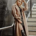 Donna bionda con cappotto lungo color cammello e stivali neri, esempio di stile sofisticato e capospalla di alta qualità