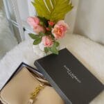 Borsa Saint Laurent beige in scatola aperta, fiori e dettagli luxury - Guida borse di lusso 2026.