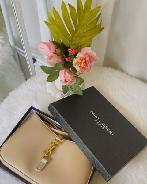 Borsa Saint Laurent beige in scatola aperta, fiori e dettagli luxury - Guida borse di lusso 2026.
