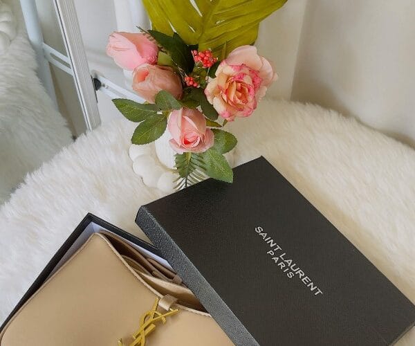 Borsa Saint Laurent beige in scatola aperta, fiori e dettagli luxury - Guida borse di lusso 2026.